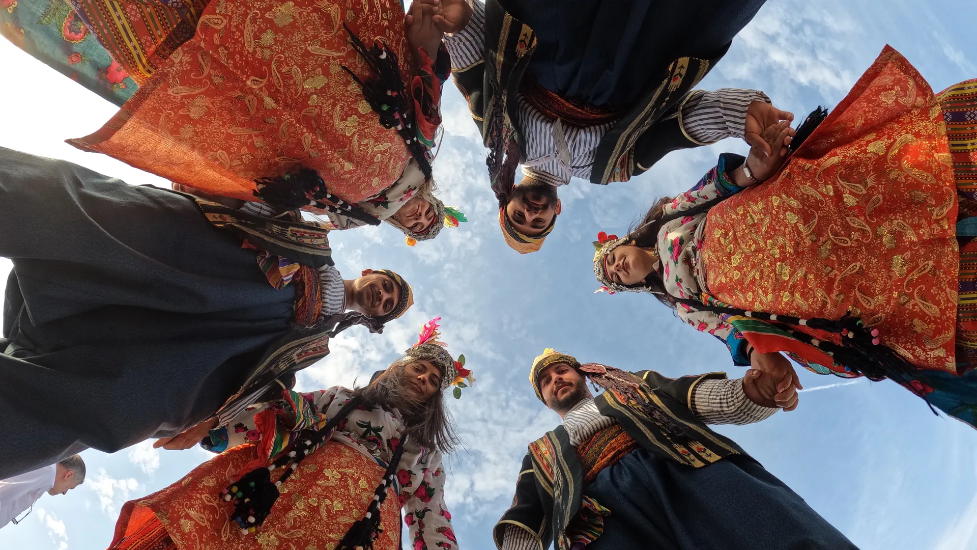 Dancers performing an energetic folk dance in dramatic red stage light